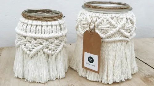 Two decorative glasses with macramé fringes on wood.