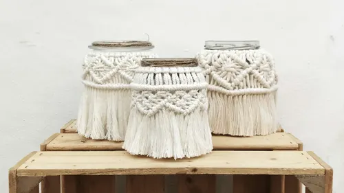 White macrame containers sit on wooden boxes.