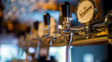 Zapfhähne füllen Bier in einer Bar mit unscharfem Hintergrund.