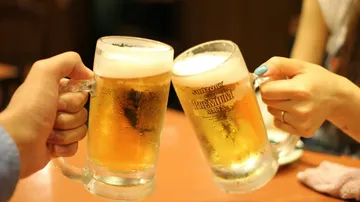 Zwei Personen stoßen mit Bierkrügen in einem Restaurant an.