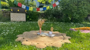 Wollteppich mit Dekoration steht auf einer grünen Wiese.