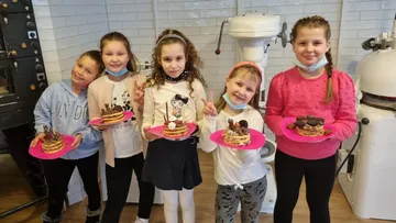 Fünf Kinder halten Kuchen in einer Bäckerei.
