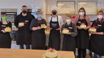 Group of people holding cake in a baking school.