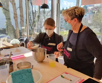 Zwei Frauen backen zusammen in einem hellen Raum.