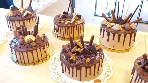 Sechs dekorierte Schokoladentorten stehen auf einem Tisch.