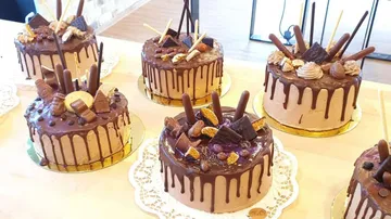 There are six decorated chocolate cakes on a table.