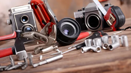 The camera lens is on a table between tools.