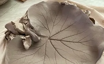 Clay plate in the shape of a leaf on a table.