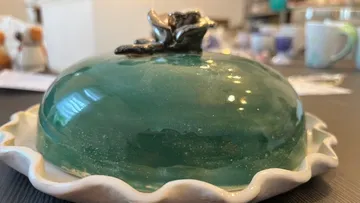 Green, smooth cake in a white bowl on table.