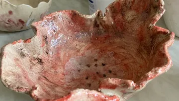 A handmade bowl shows irregular, red color patterns.