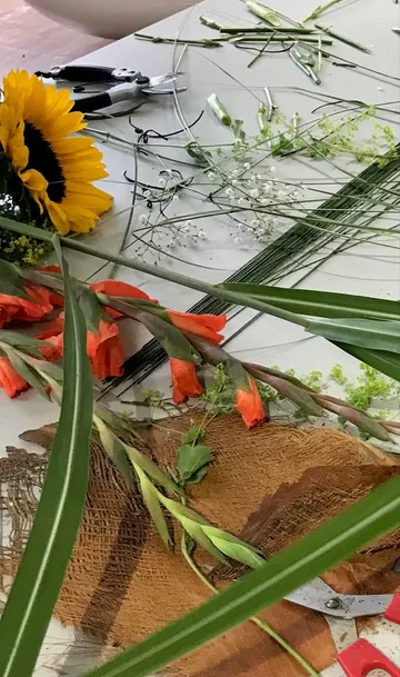 Blumen und Werkzeug liegen auf einem Arbeitstisch verteilt.
