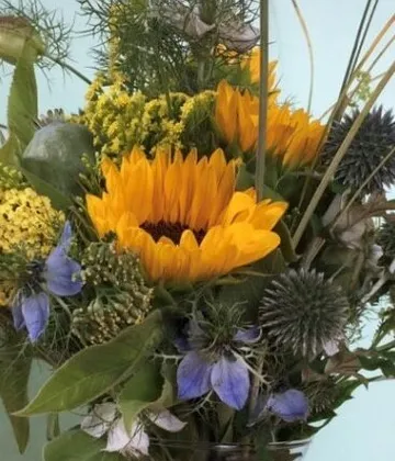 Ein Strauß bunter Blumen steht vor einem hellblauen Hintergrund.