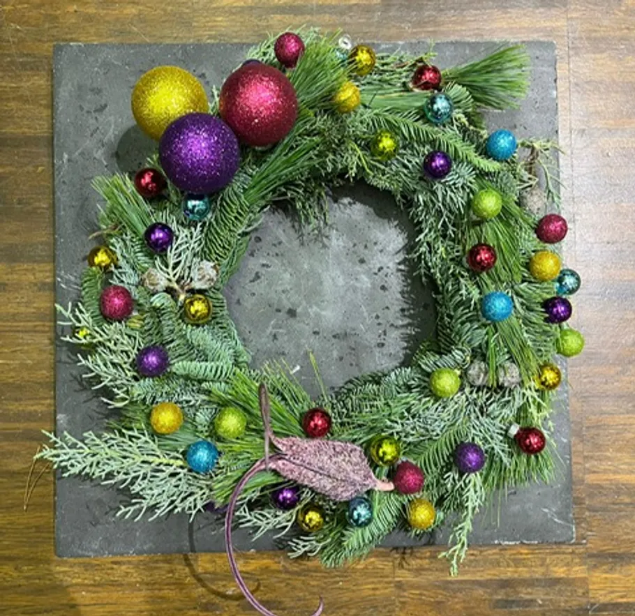 Ein bunter Weihnachtskranz liegt auf einem Tisch.