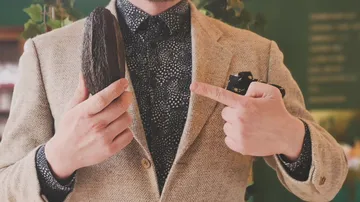 Mann zeigt auf Kakaobohne in stilvollem Outfit.