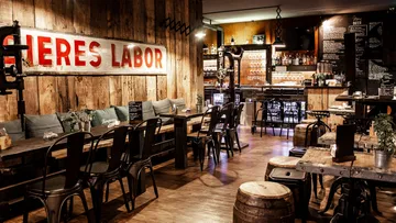 Rustic restaurant with tables, chairs and a bar.
