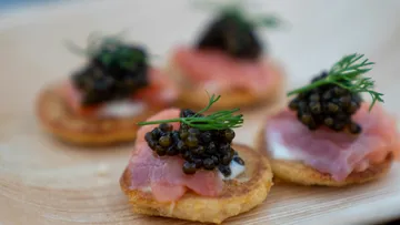 Spoons with ham and caviar, elegantly arranged.
