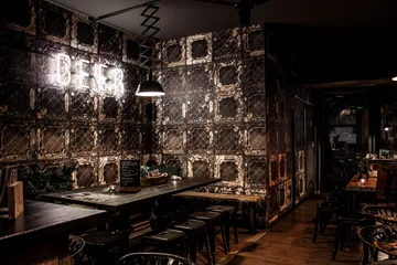 Illuminated “BEER” neon table in rustic restaurant with chairs.