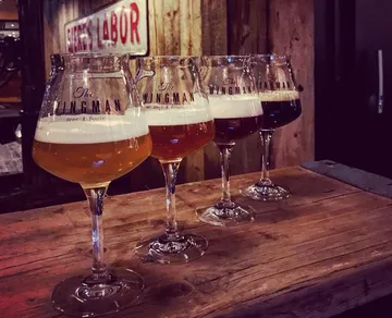 Four glasses of beer stand on a wooden surface.