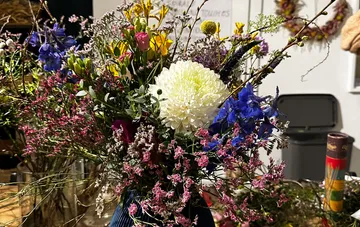 Colourful flowers in a vase surrounded by various objects.