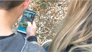 Zwei Personen betrachten zusammen ein Smartphone im Freien.