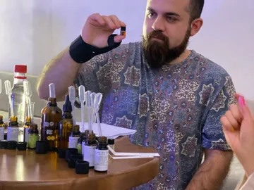 Man holds bottles while working at a table with others.