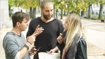 Drei Menschen diskutieren, während sie in einem Park stehen.