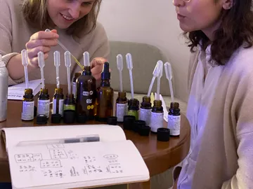 Two women mix essential oils at a table.