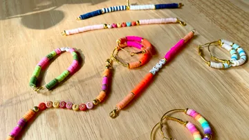 Bunte Armbänder liegen auf einem hellen Holzuntergrund.