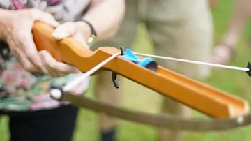 A wooden crossbow is held ready for outdoor shooting.