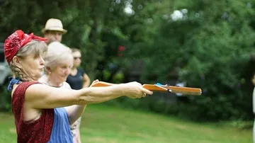 Woman aims with a toy gun in the garden.