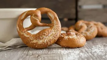 Brezel mit Menschenfigur, auf Holzunterlage, umgeben von Gebäck.