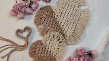 Herzförmige Untersetzer liegen auf einem weißen Tisch mit Blumen.