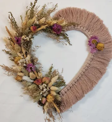 Heart-shaped wreath made of dried flowers and fringes.