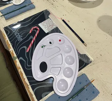 Color palette is on table with painting tools and candy.