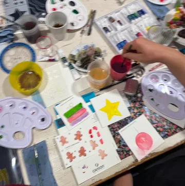Farben und Materialien auf Tisch, Hand malt mit Pinsel.
