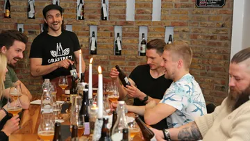 Group of men sitting at table enjoying beer.