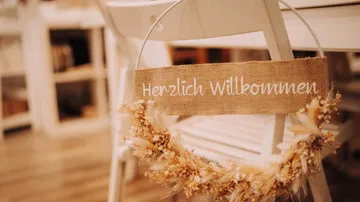 Willkommensschild hängt an einem Stuhl in einem Raum.