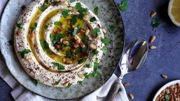 Hummus served with olive oil, pine nuts and herbs.