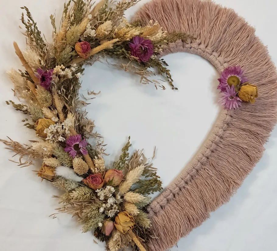 Herzförmiger Kranz mit getrockneten Blumen auf Stoff.