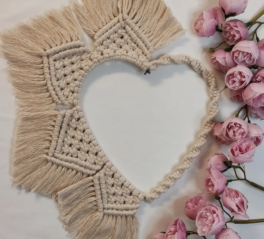 Macrame heart wreath with pink flowers.