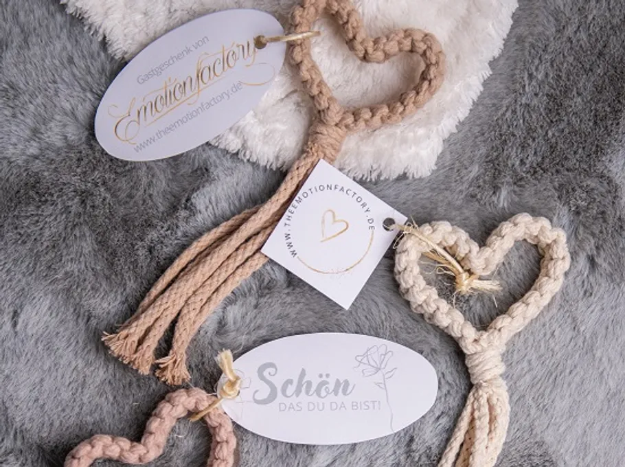 Braided heart keychains with tags on fuzzy fabric.