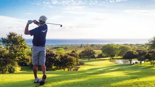 Golfer swings the club on a green field.