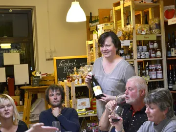 A woman serves wine in a grocery store.