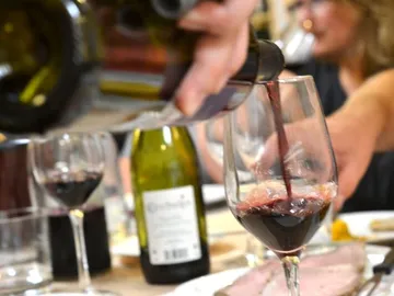 Red wine is poured into a glass to enjoy the meal.