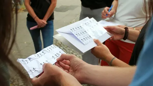 Sheets of paper with drawings are held by several people.