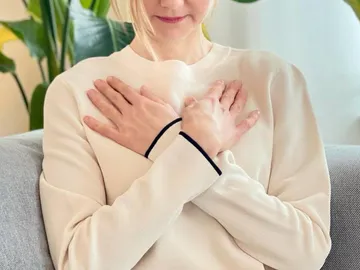 Frau umarmt sich in einem gemütlichen Raum mit Pflanzen.