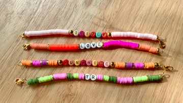 Colourful bracelets lie on a wooden table.