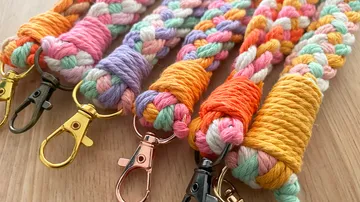 Colourful, braided leashes with snap hooks lie on wood.