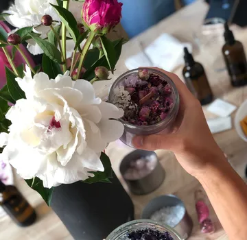 Eine Hand hält ein Glas mit getrockneten Blumen.
