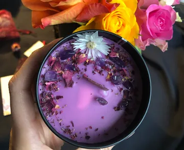 Purple candle with flowers and crystals in hand